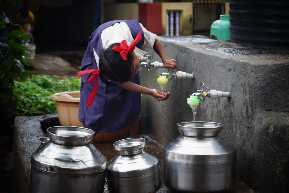 Schoolgirl collecting water from community taps