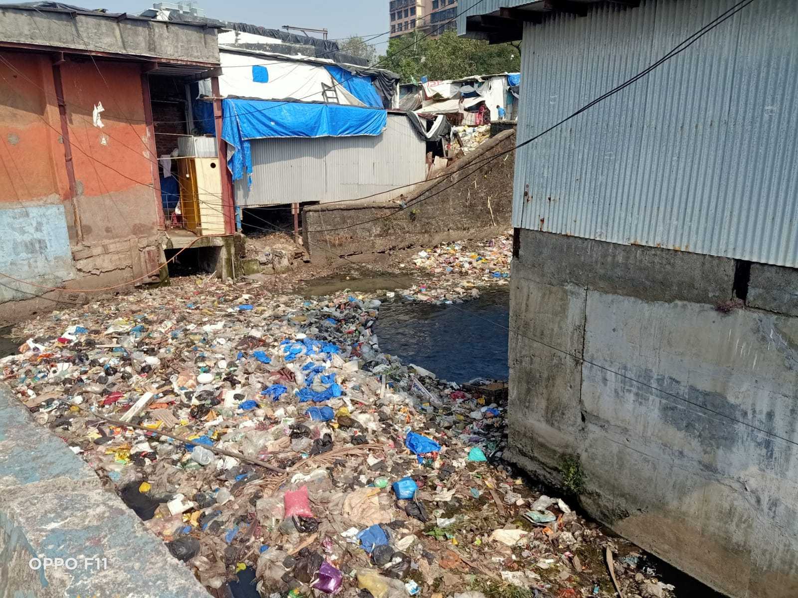 Waste-filled drain beside homes in a settlement